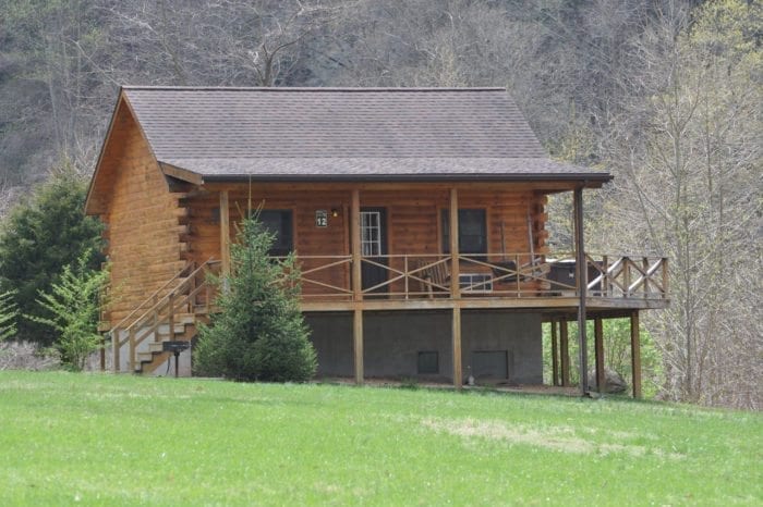 An exterior view of a wood log cabin with outdoor deck