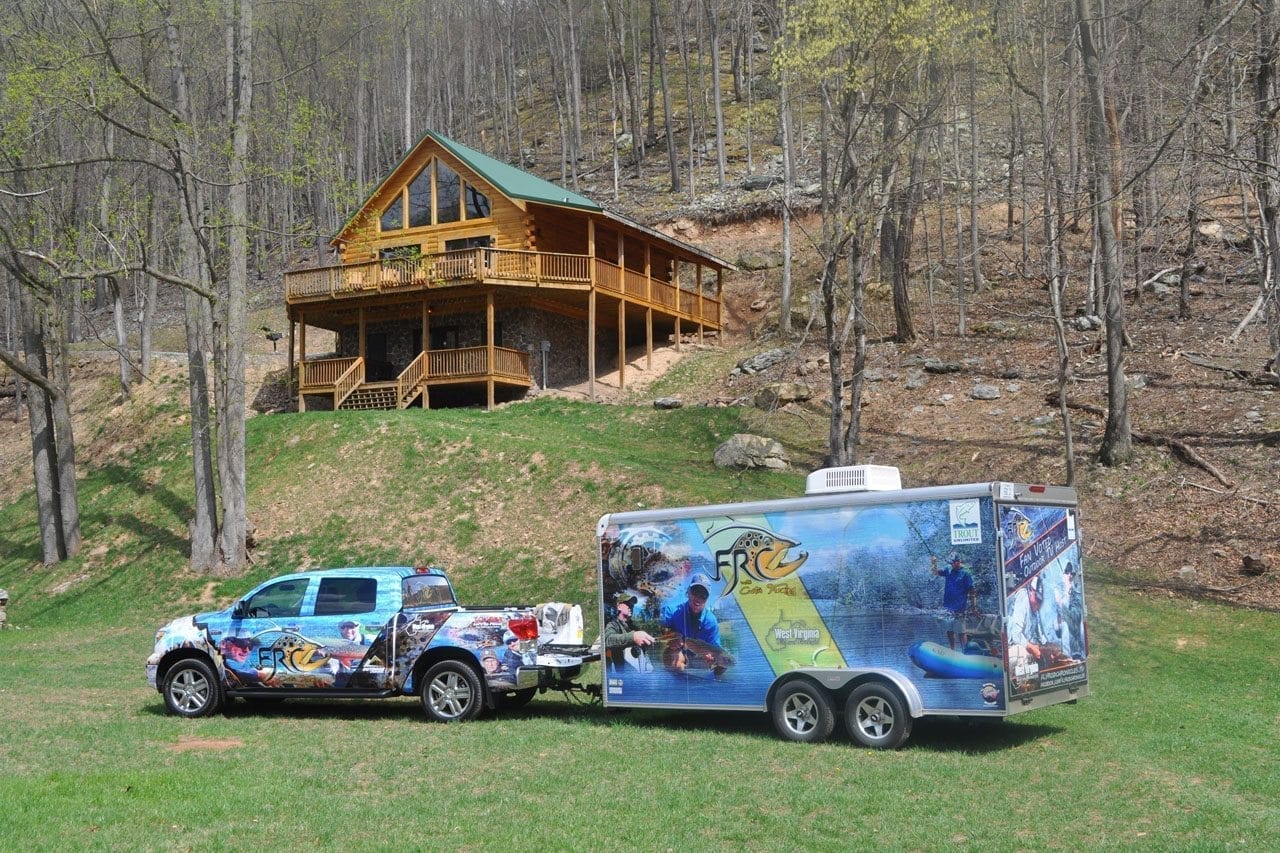 View of Fly Rod Chronicles truck and trailer in foreground and log cabin in background