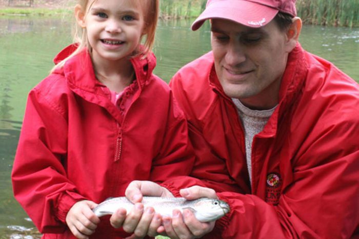 A father and daughter holding a fish
