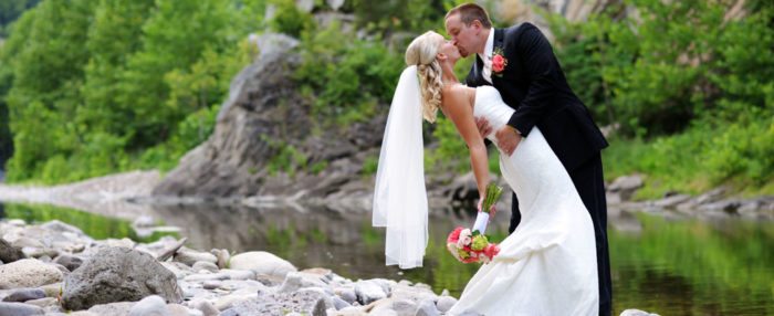 A bride and groom standing next to a calm river during a West Virginia wedding.