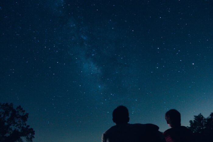 Two people looking up at the night sky filled with stars.